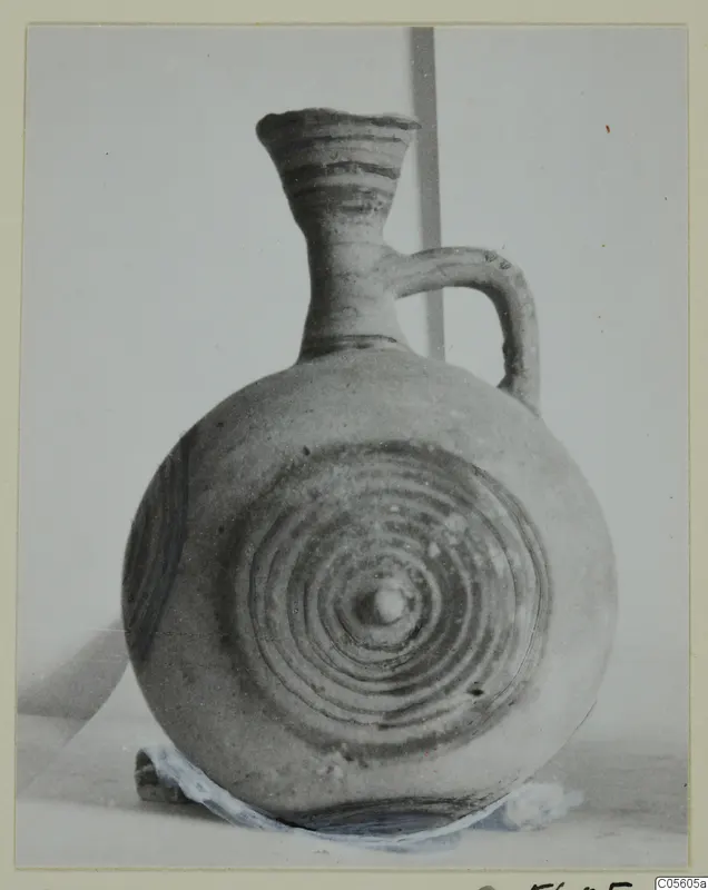 Pottery White Painted I jug with a flaring neck, a strap handle and concentric circles on its body