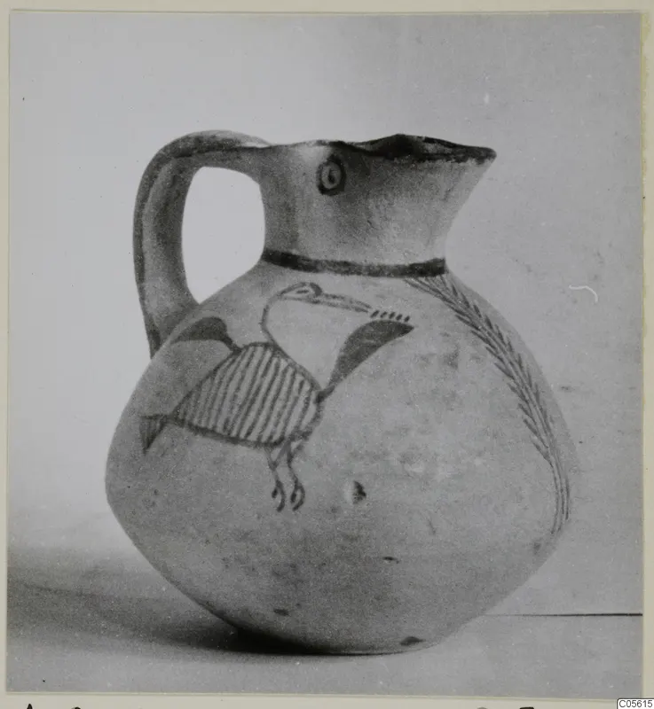White Painted IV juglet with a bird and a branch-like pattern painted in dark paint on a pale body.