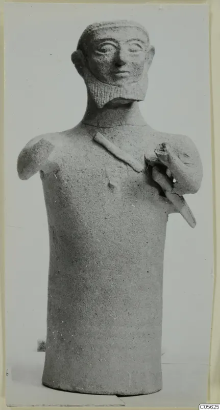 Terracotta figurine of a bearded figure with a cylindrical body and one raised arm, from Ayia Irini
