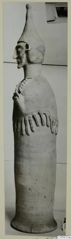 Terracotta Proto-Cypriote I, a tall standing figure in profile with a tapering cap and arms bent across the chest