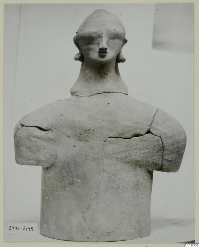 Terracotta figure with folded arms and a rounded head, photographed from the front at Ayia Irini
