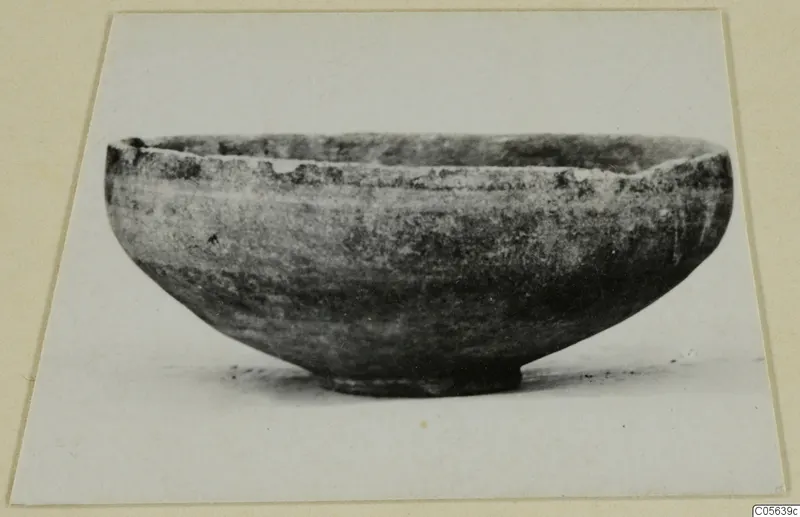 Pottery Black-on-Red II-IV bowl with a rounded body and short ring foot, shown in side view