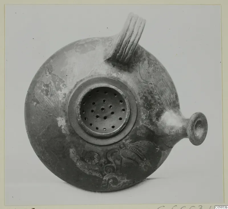 Round pottery vessel with a ribbed strap handle, a small spout and a pierced disc on top, decorated with painted motifs.