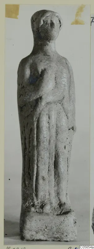 Small standing figurine on a rectangular base, photographed from Marion, finds from tombs 31–45 series.
