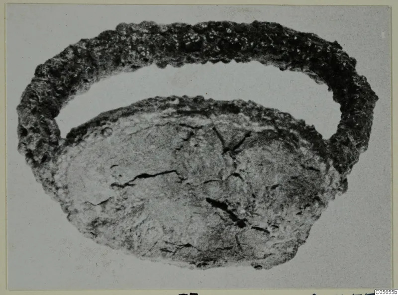Corroded metal ring with a flattened oval piece below it, from Marion.