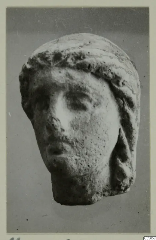 Small pale head with hair drawn back over the top and sides, from the Marion finds from tombs 46–60