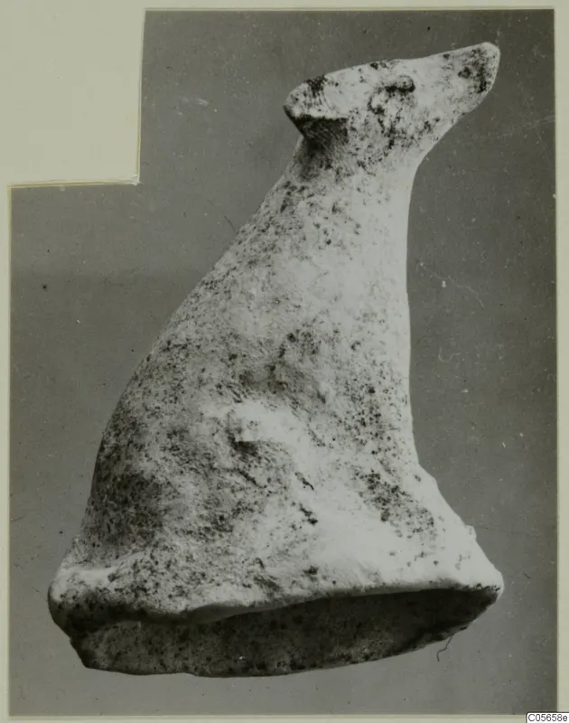 Terracotta figurine of an animal with a long raised neck, small pointed head and flat base, against a grey backdrop