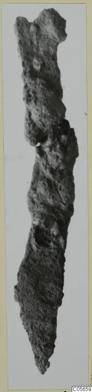 Corroded iron knife from Marion Tomb 75, shown upright against a pale background.