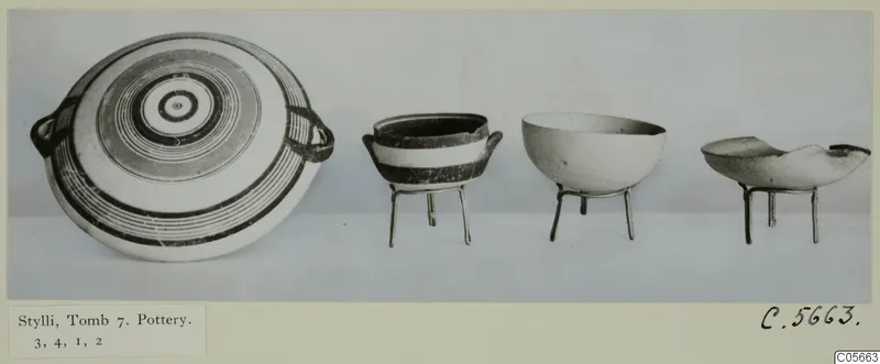 Four pottery vessels from Stylli, Tomb 7, shown in a row against a grey backdrop.