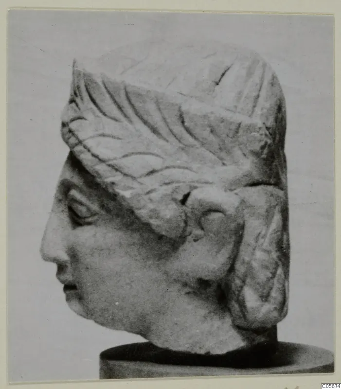 Limestone head of a figure from Mersinaki, shown in profile on a round dark base