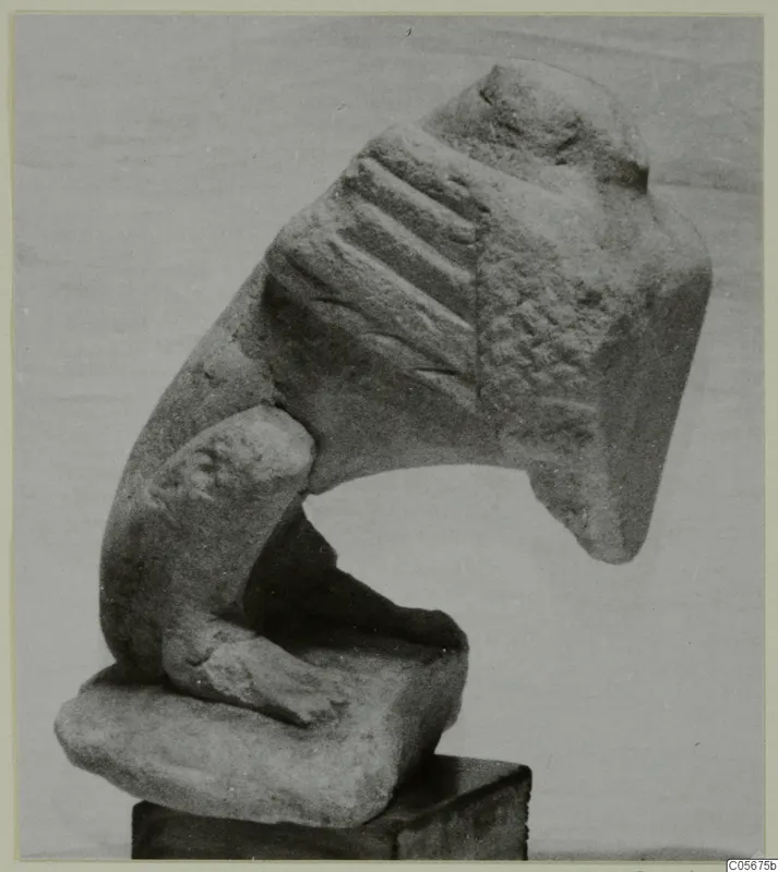 Limestone sculpture fragment from Vouni, with a grooved upper section and a small limb-like projection, set on a wooden block