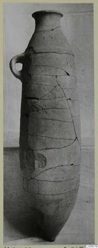 Tall reconstructed pottery pithos from Marion with a narrow neck and a single loop handle, photographed against a plain backdrop