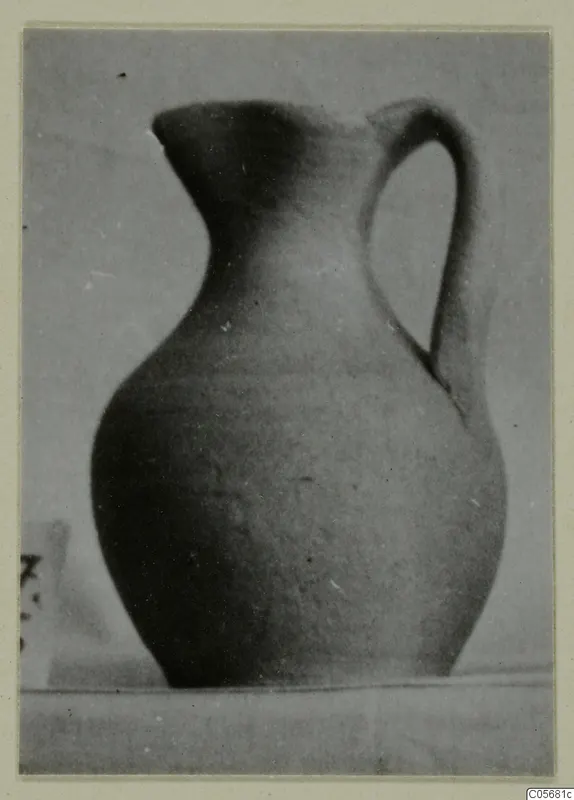 Pottery juglet, Plain White VI, with a single handle, shown against a grey backdrop