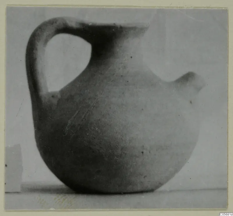 Plain pottery jug with a strap handle and a spout, photographed against a plain background.