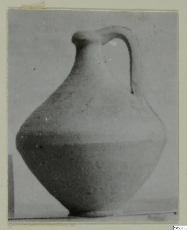 Plain pottery jug with a single strap handle, shown against a plain grey backdrop.