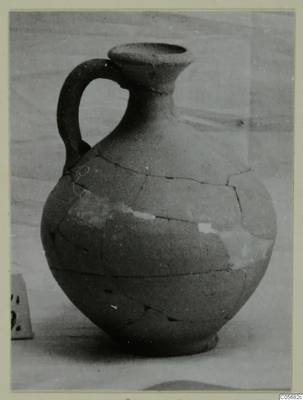 Pottery Plain White VII jug from Marion with one handle, cracked and partly restored, against a plain background.