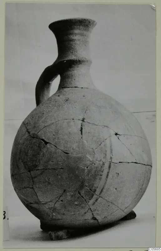 Jug with a single strap handle, a flaring neck and a rounded body, photographed against a plain pale background