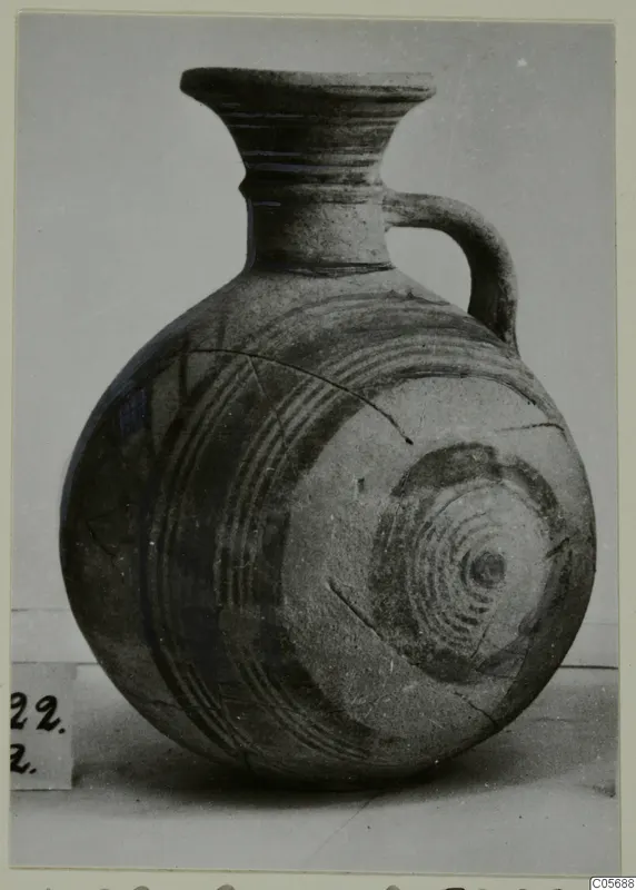 Round-bodied jug with a flared neck and a single loop handle, decorated with concentric painted circles.