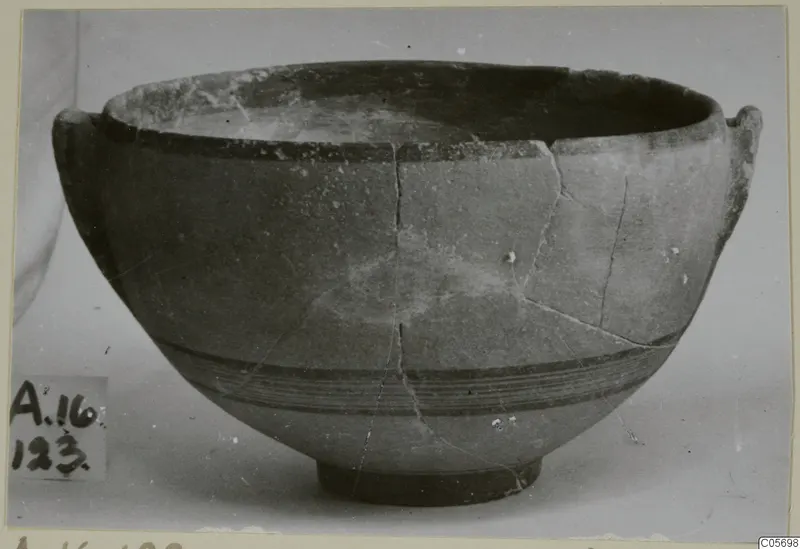 Pottery Black-on-Red I-III bowl with two small handles and dark bands around the body, seen from the side