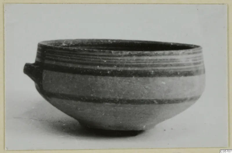 Pottery bowl from Amathus with a small lug handle and dark horizontal bands, seen from the side.