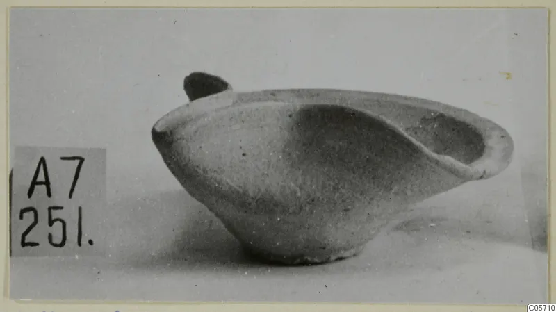 Terracotta lamp from Amathus with a rounded body and a small handle, photographed in side view.