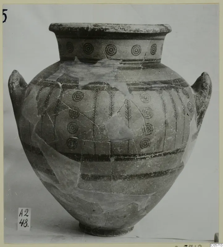 Pottery Black-on-Red amphora from Amathus with concentric circles and vertical bands, photographed against a grey backdrop