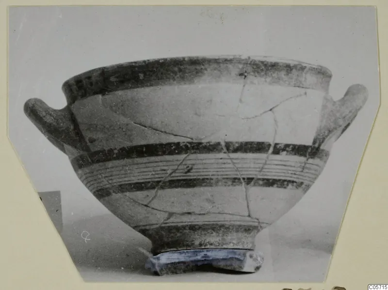 Two-handled bowl with dark painted bands and a footed base, photographed on a cream card mount, from the Amathus tombs series