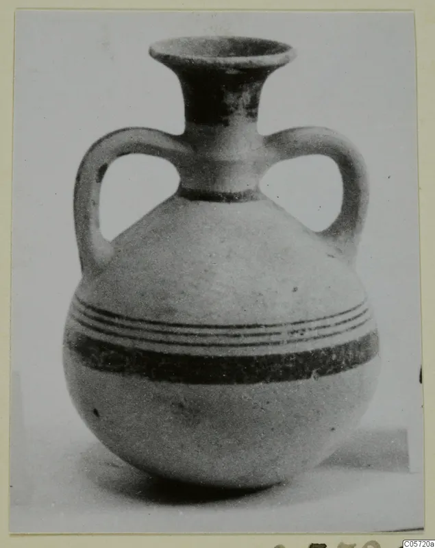 Two-handled jug with a flared neck and dark painted bands around the rounded body, photographed on a pale ground