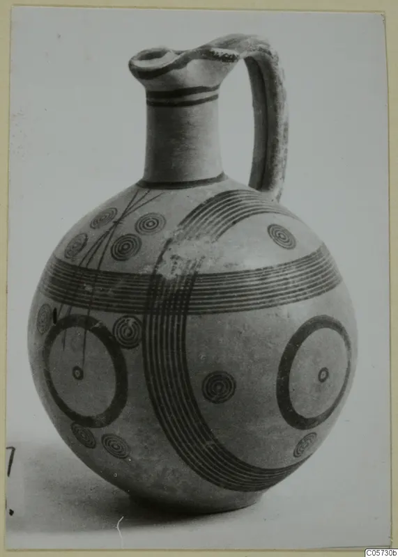 Jug with black painted bands, concentric circles and large rings, from the Pottery Black-on-Red II-IV series.