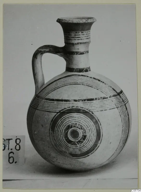 Pottery Bichrome III jug with a flared neck, a single loop handle and concentric circles painted on its body.