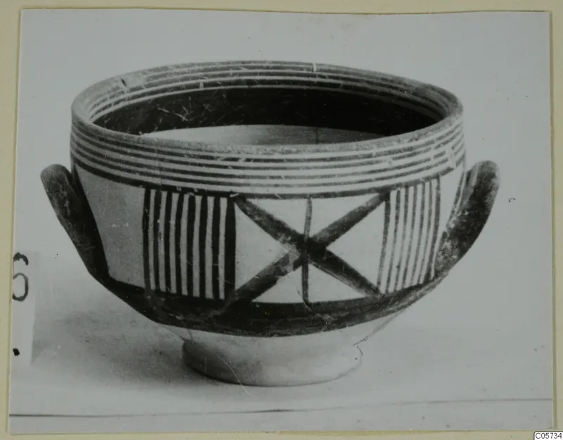 Pottery bowl with two small loop handles, painted with bands, vertical stripes and a cross pattern on the body.