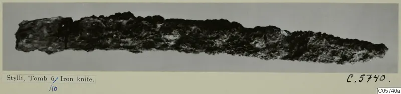 Corroded iron knife from Stylli, Tomb 6/10, shown horizontally against a grey background