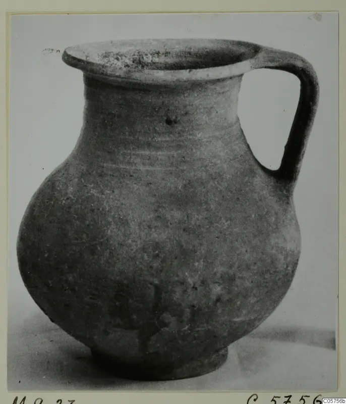 Jug with a wide flared rim, single loop handle and rounded body, photographed on a plain background.