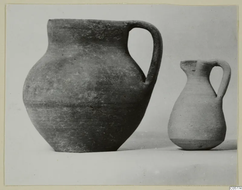 Two pottery jugs with single strap handles, photographed side by side against a plain background.