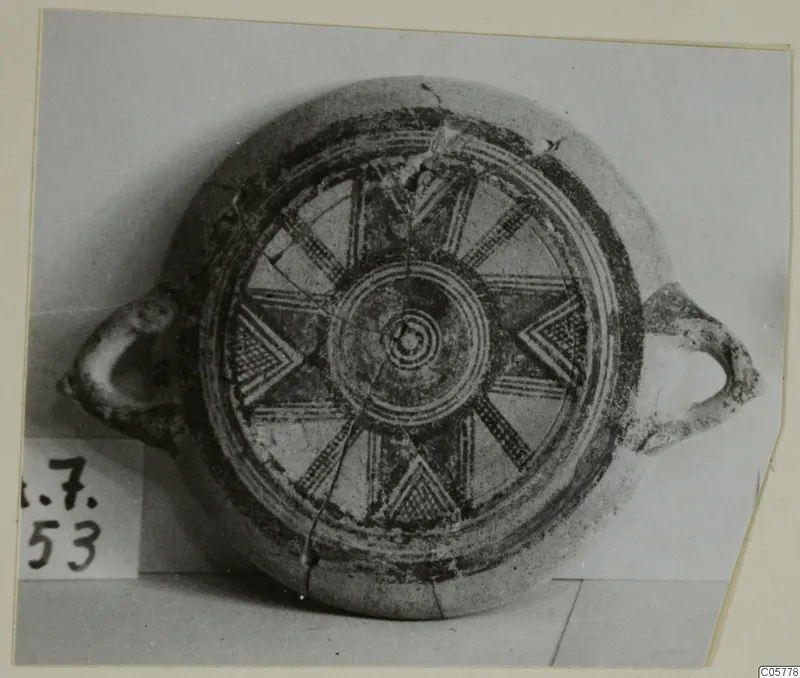 Plate with two loop handles, its interior painted with concentric rings, radiating spokes and chevrons in dark paint