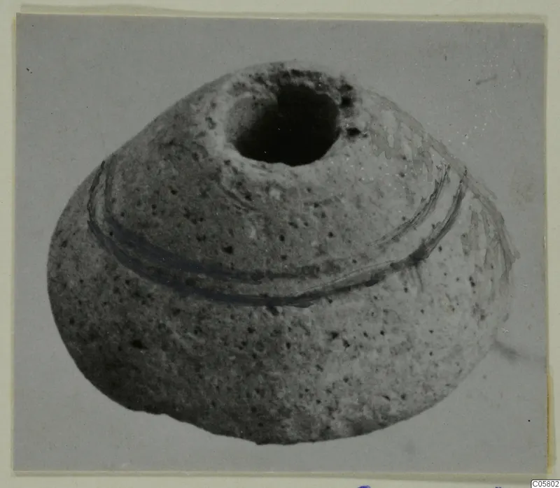 Rounded, squat object with a wide dark opening at the top and two dark bands encircling its body, photographed on a grey background.