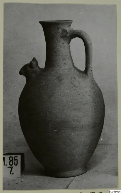 Pottery jug with a tall neck, a loop handle and a small projecting lip