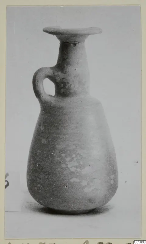 Pottery Red Slip jug with a flared rim and a single loop handle, photographed upright