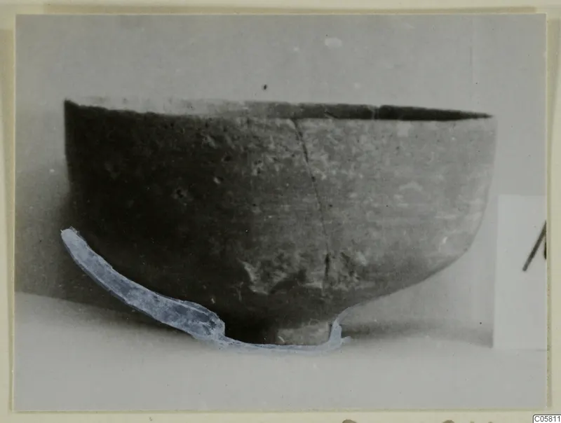 Pottery bowl with an uneven rim and a long crack down its side, seen from the side