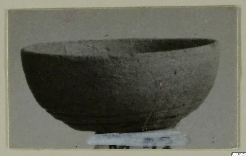 Pottery Plain White VI bowl seen from the side, standing on a pale paper label at its base