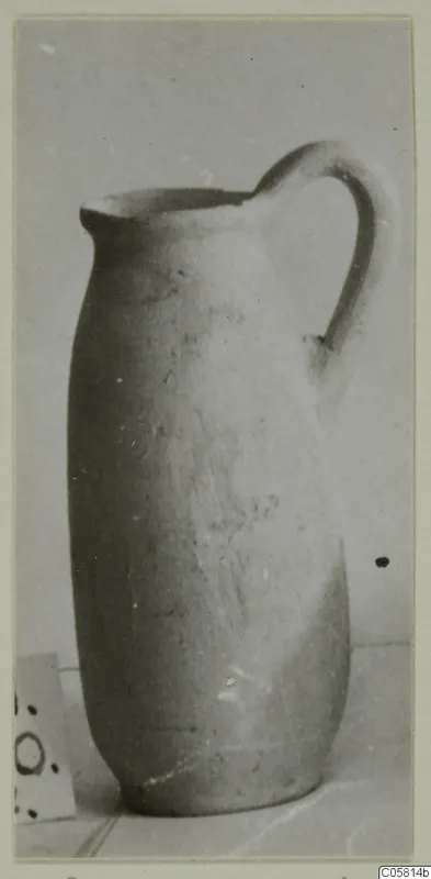 Tall jug with a single strap handle and a pinched spout, shown on a plain backdrop.