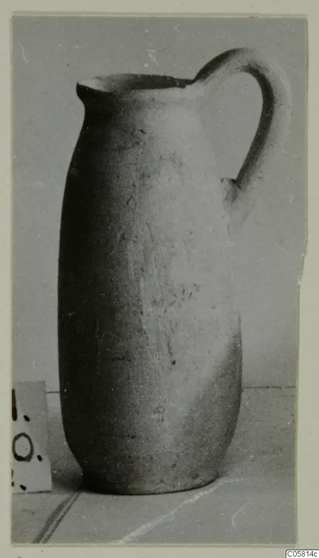 Plain pottery jug with a single loop handle and a trefoil-like pouring lip, shown on a plain surface.