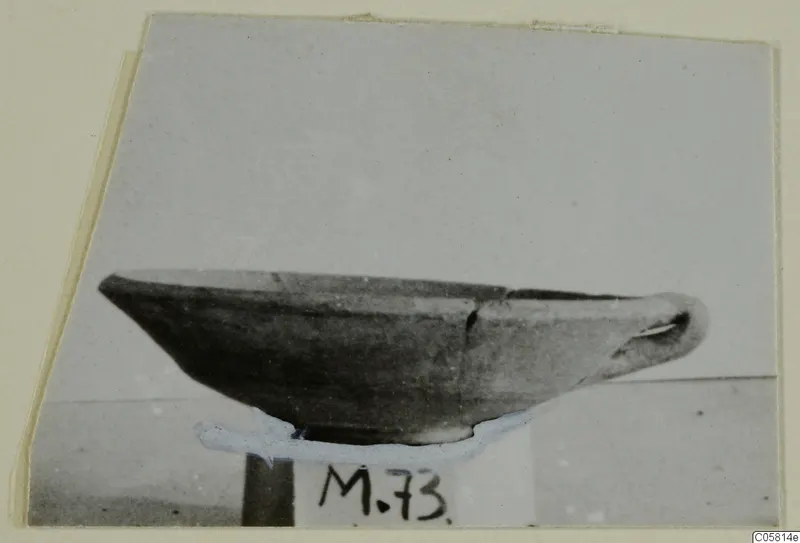 Pottery Red Slip bowl in side view, standing on a small stand with a number label