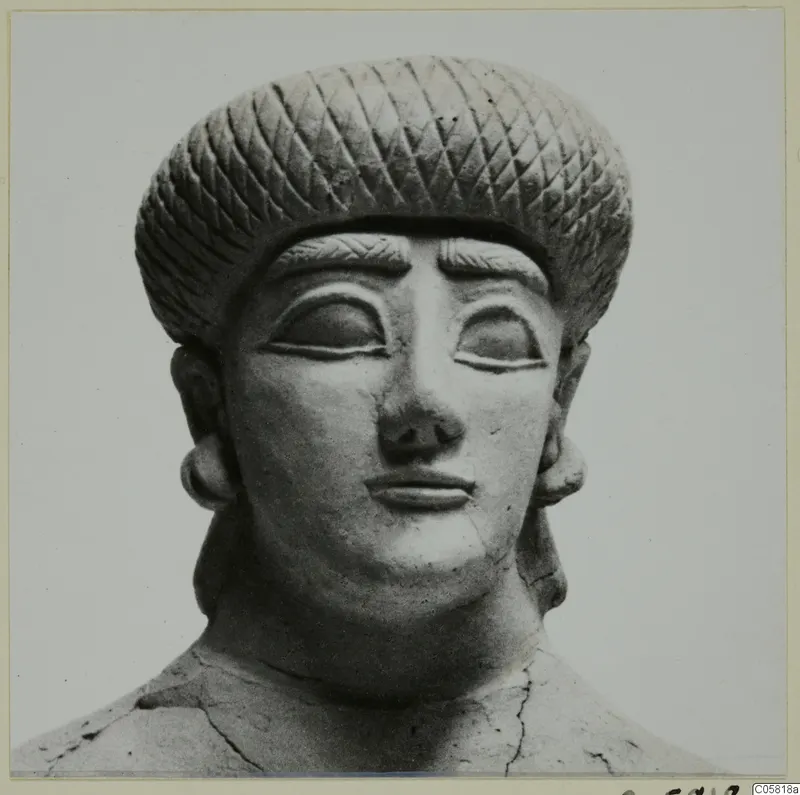 Terracotta head and shoulders of a figure with a diamond-patterned headdress and heavy-lidded eyes