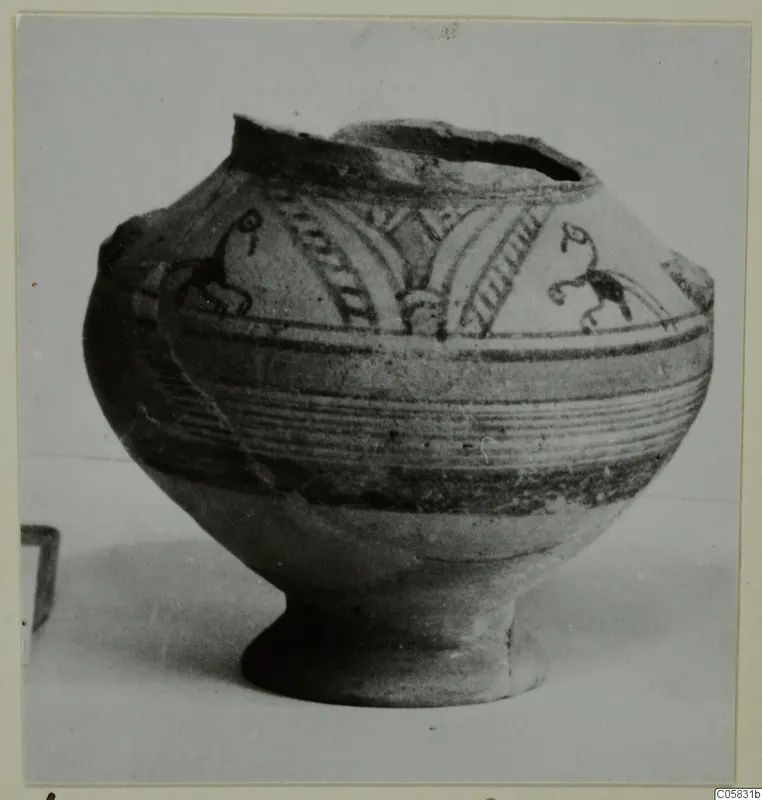 Pottery Bichrome V vessel with a round body, high foot and dark painted bands and motifs, photographed on a pale surface
