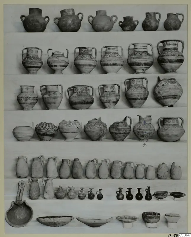 Rows of pottery vessels from a deposit at Idalion, jugs, bowls and small juglets set out on a white cloth.