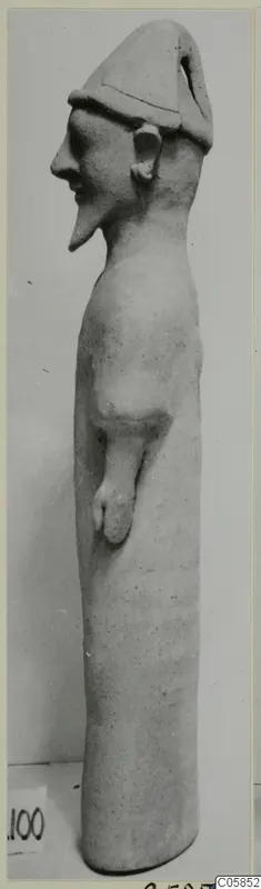 Tall terracotta standing figure with a conical cap, seen from the side against a plain background