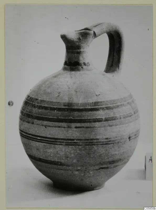 Pottery Bichrome V jug with a tall neck, strap handle and dark painted bands around the body