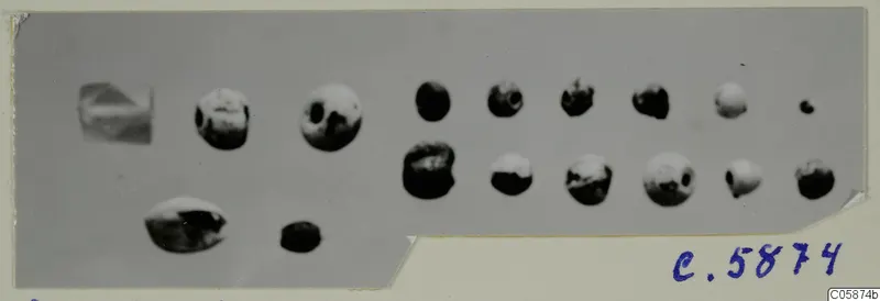 Group of small round beads and a few irregular jewellery parts, shown on a grey background