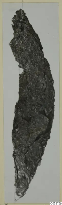 Corroded iron knife from Idalion, shown upright on a card mount against a pale background.